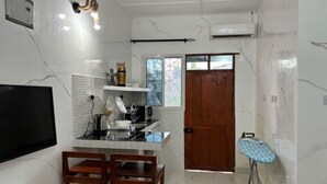 Cocina compacta con televisor, comedor y un pequeño centro de planchado.