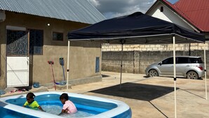 Una piscina al aire libre en una zona residencial, con un coche aparcado cerca.
