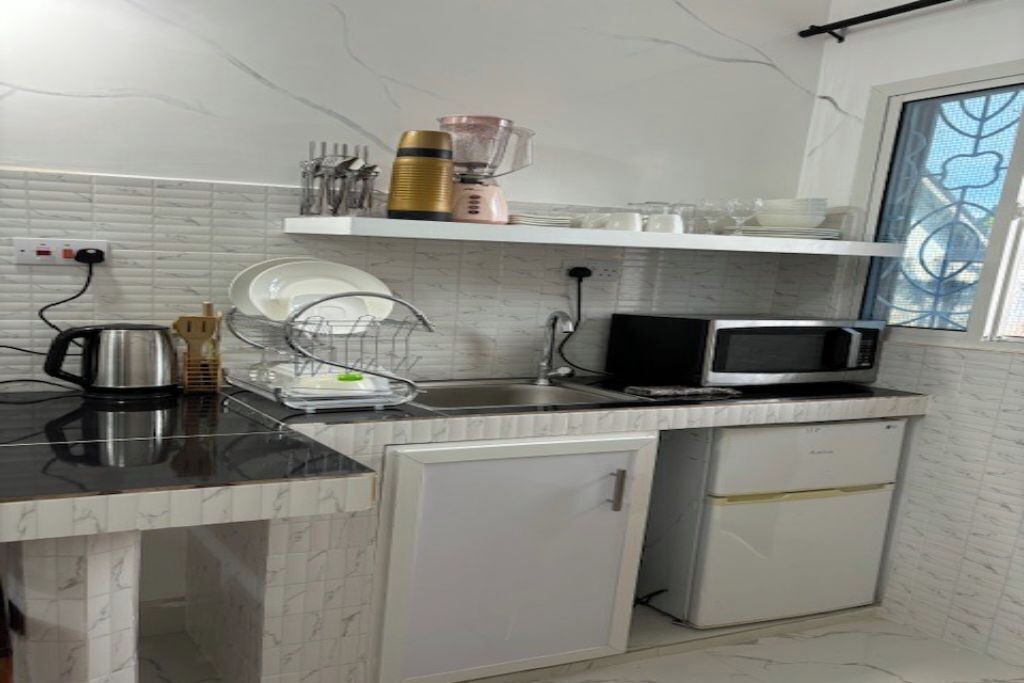 Una cocina compacta equipada con microondas, un refrigerador pequeño, un escurreplatos y una cafetera.