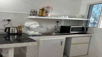 Una cocina compacta equipada con microondas, un refrigerador pequeño, un escurreplatos y una cafetera.