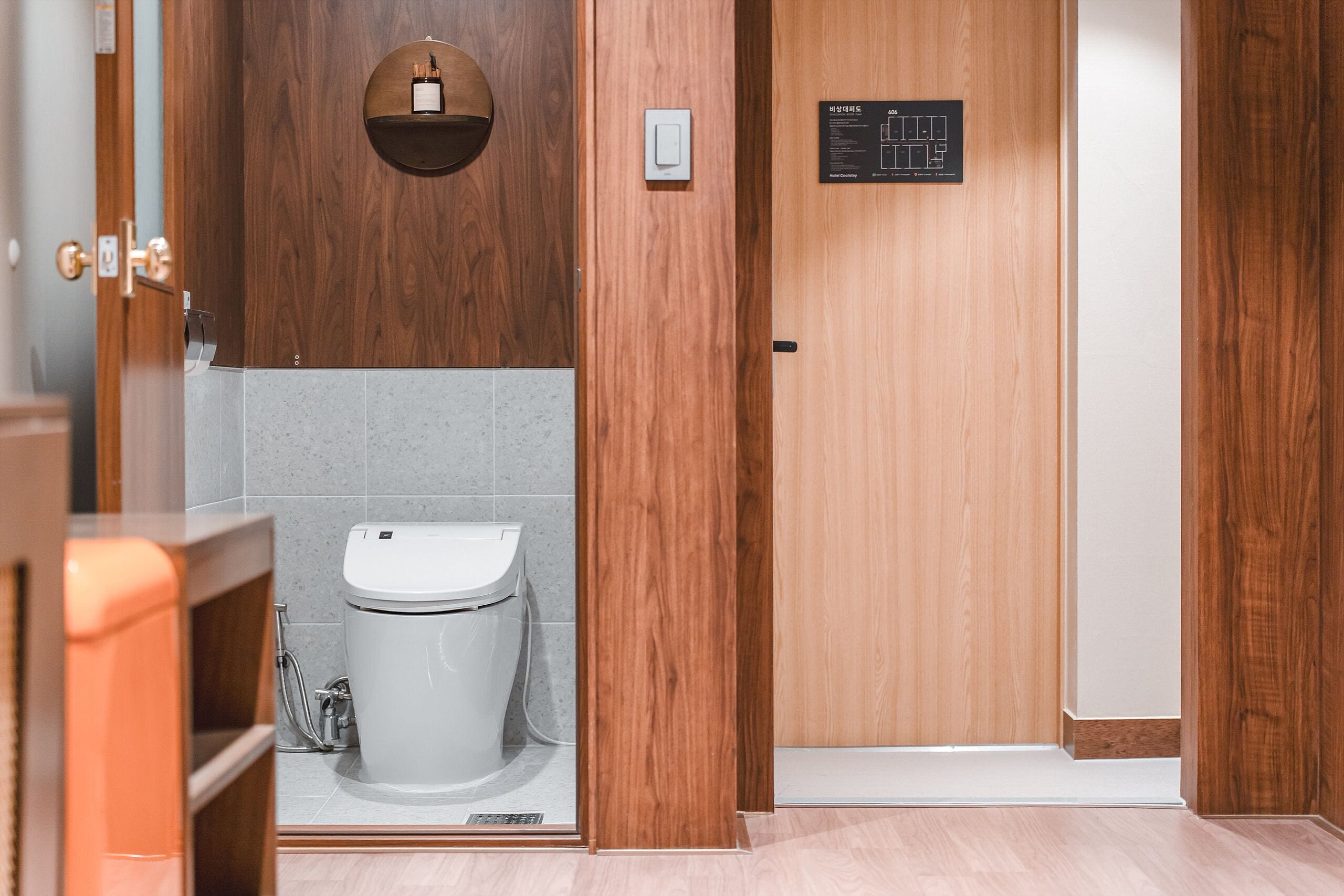 Baño de madera con inodoro, lavamanos y ducha. Hay una puerta de madera con un letrero encima.