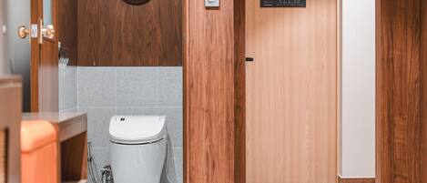 Baño de madera con inodoro, lavamanos y ducha. Hay una puerta de madera con un letrero encima.