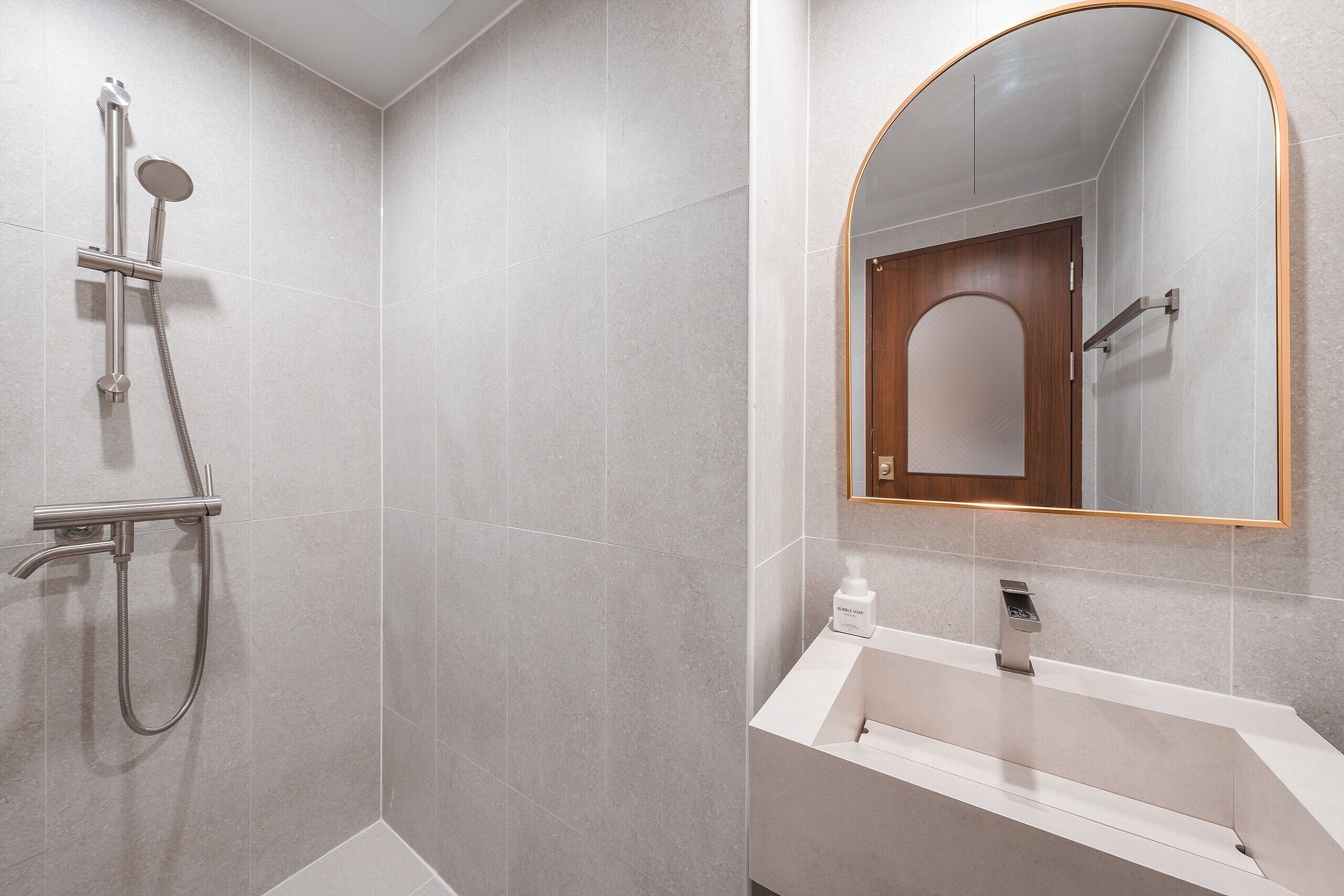 Un baño moderno con ducha, lavamanos y espejo con marco de madera.