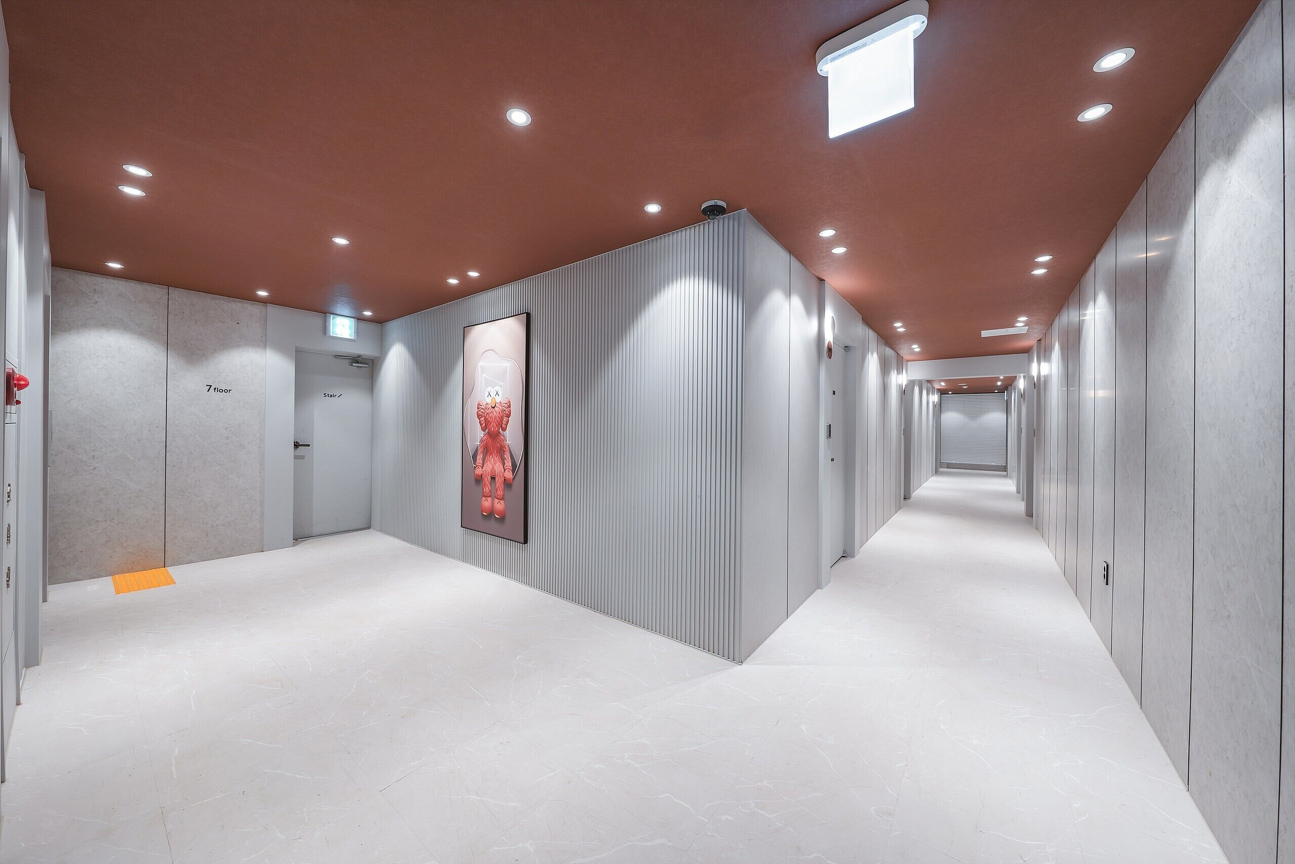 A modern hotel corridor with a 7-floor sign, a staircase, and a corridor leading to a door.