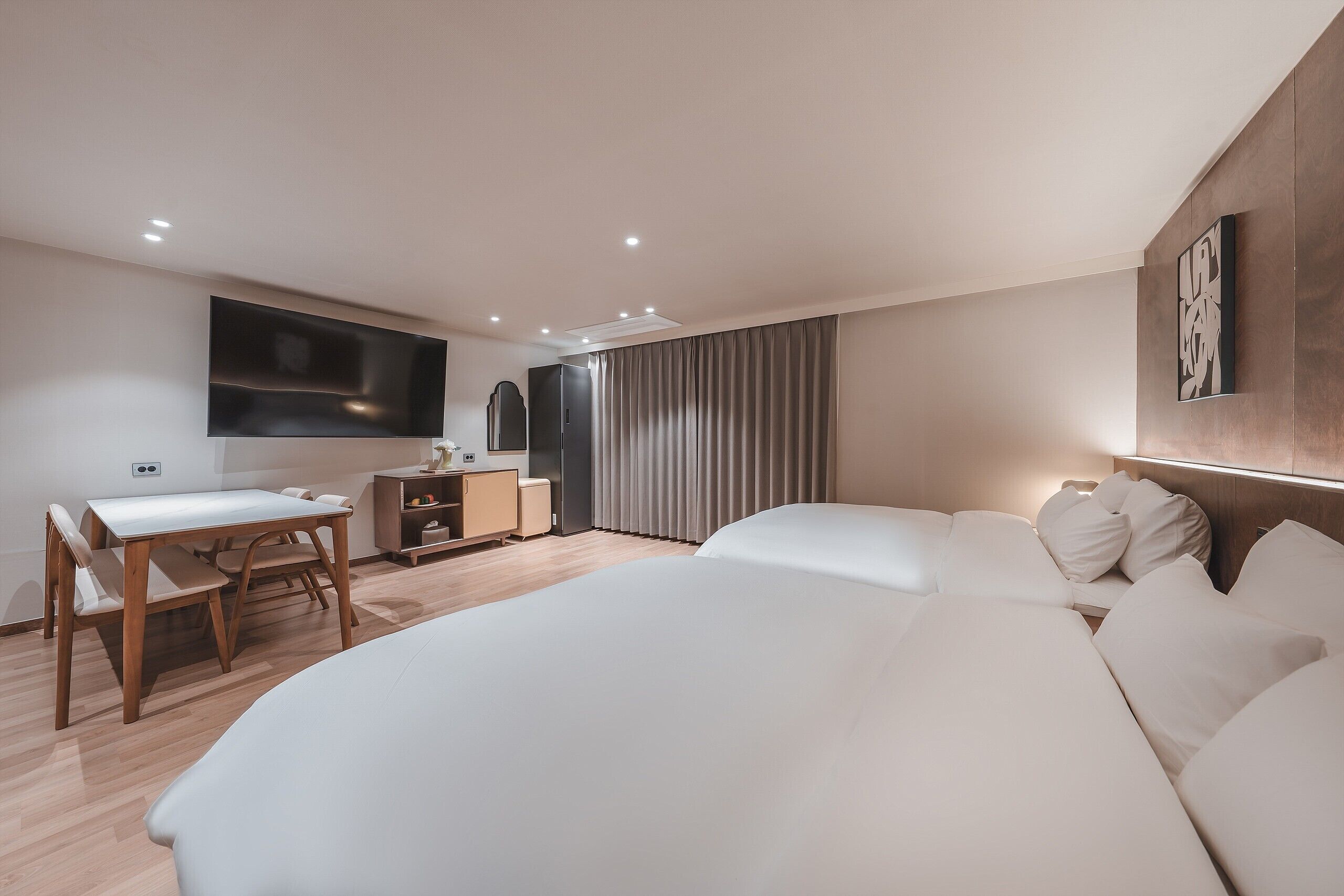 A modern hotel room with a large bed, a desk, and a flat-screen TV mounted on the wall.