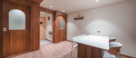 A modern hotel room with a wooden door, a white table, and two chairs.