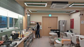 A modern kitchen with a person preparing food, equipped with a stove, sink, and various cooking utensils.