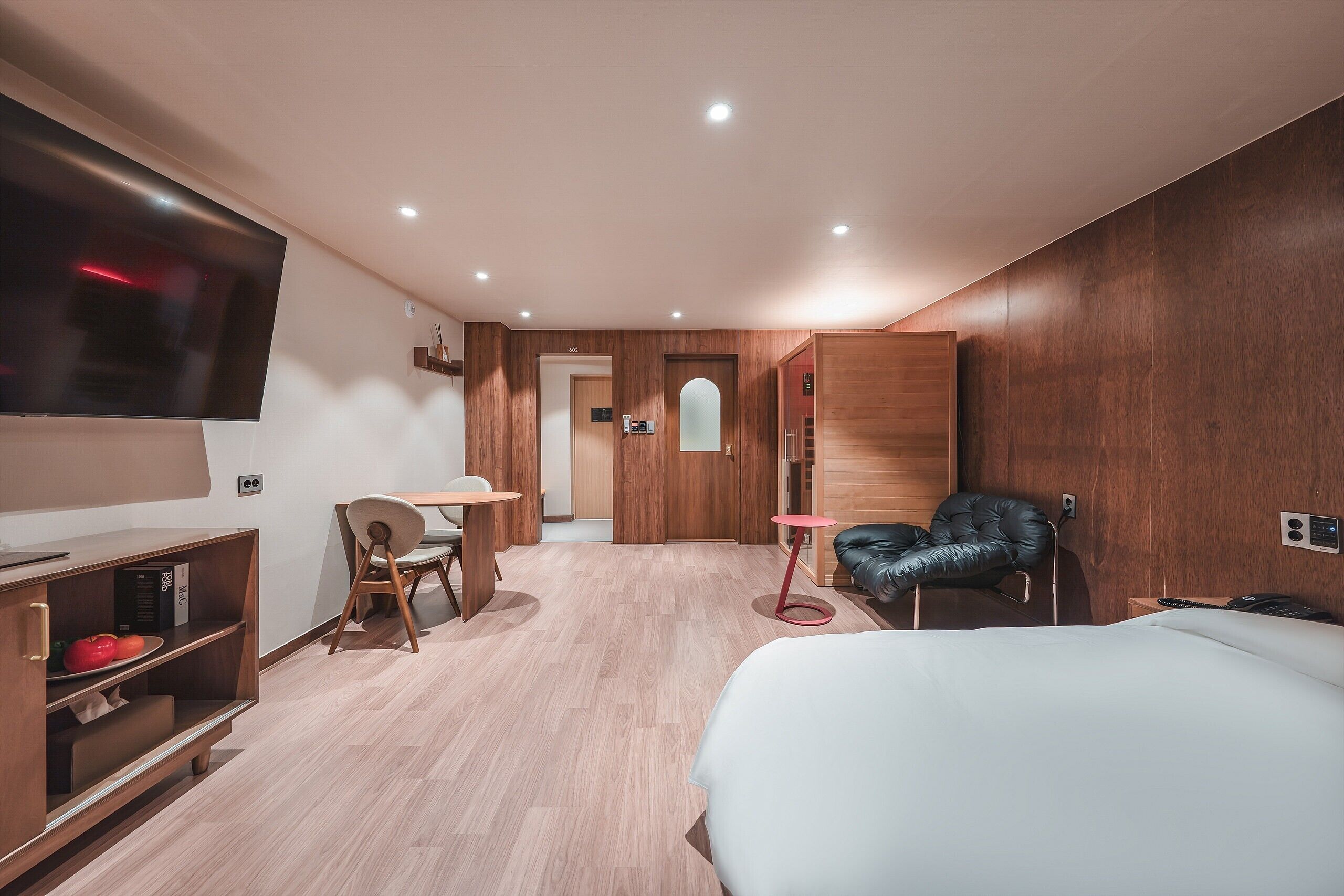 Una habitación de hotel moderna con cama, escritorio, silla, televisor y armario.