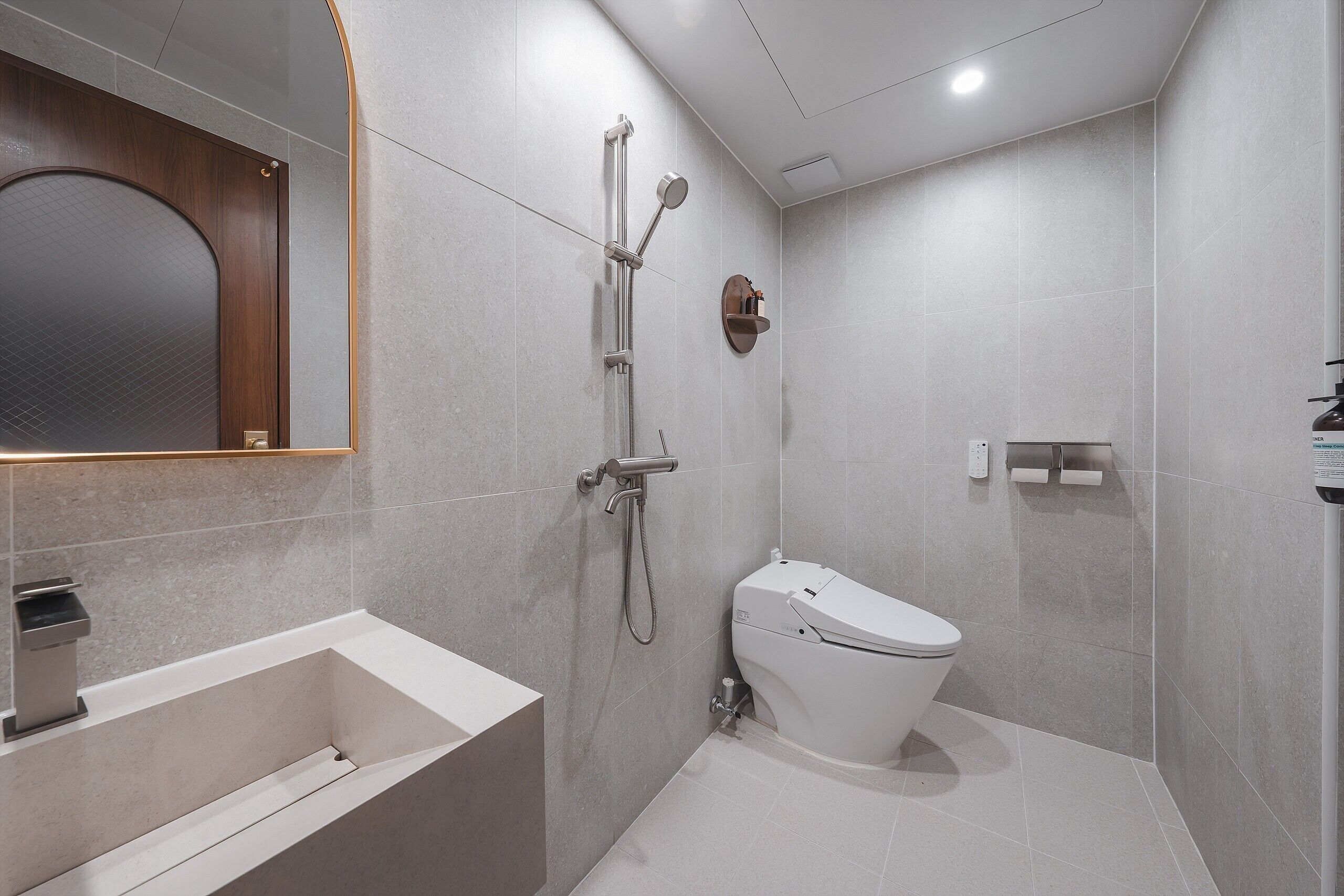 A modern bathroom with a bathtub, toilet, and shower.