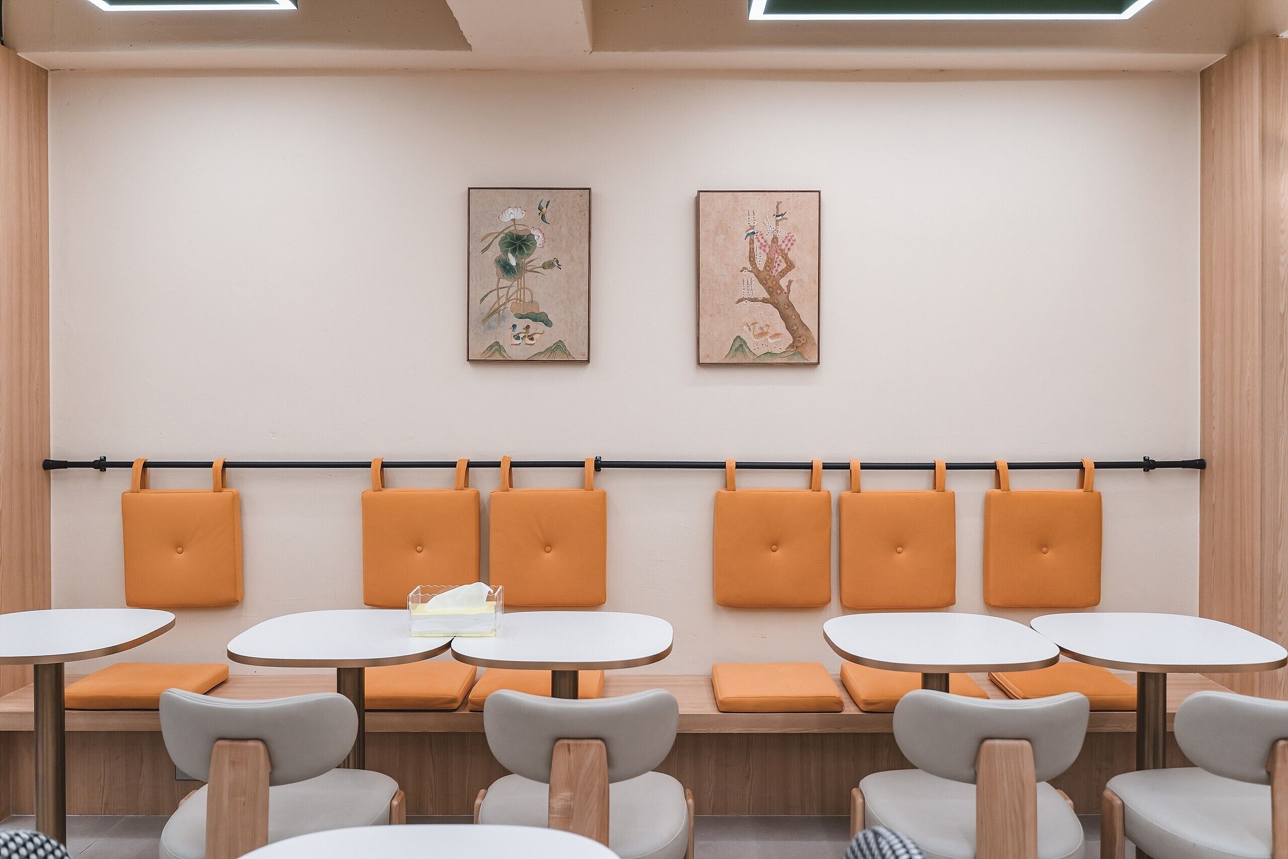 A modern interior with seating areas, tables, and artwork on the walls.