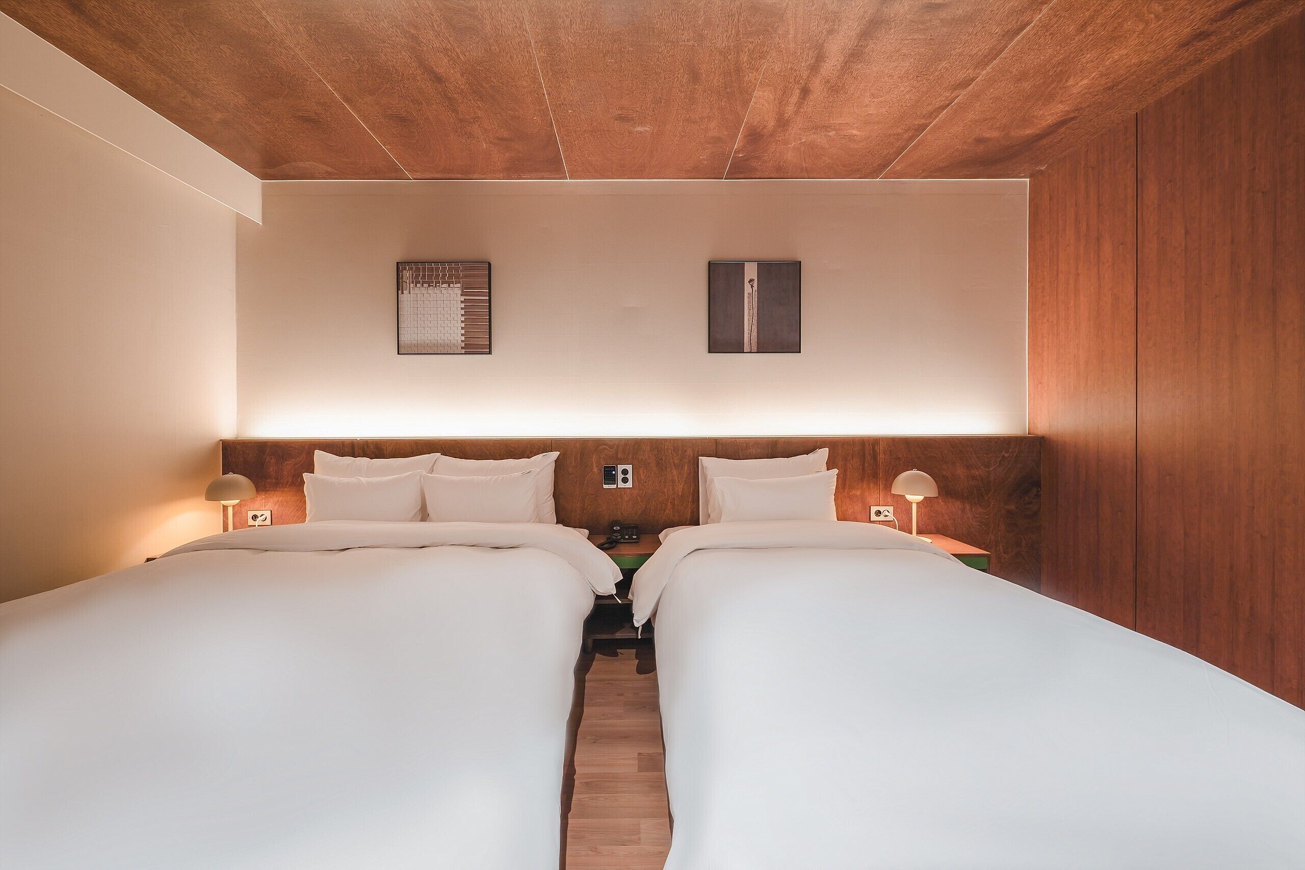 A double room with two beds, wooden headboard, bedside tables with lamps, and a wooden ceiling.