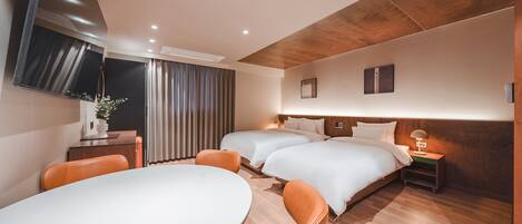 A modern hotel room with a large bed, a desk with a chair, a TV mounted on the wall, and a window with curtains.