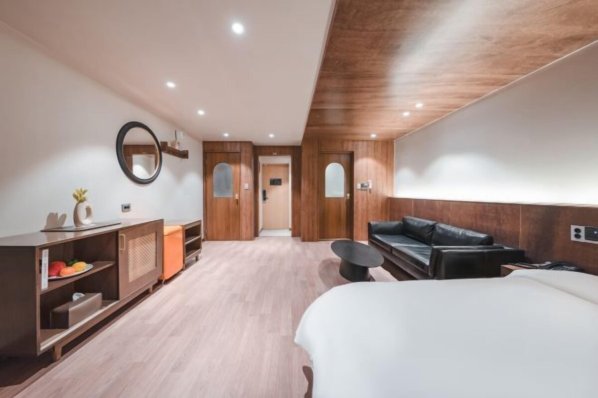Habitació d'hotel moderna amb un llit gran, un sofà, una taula petita i televisió integrada.