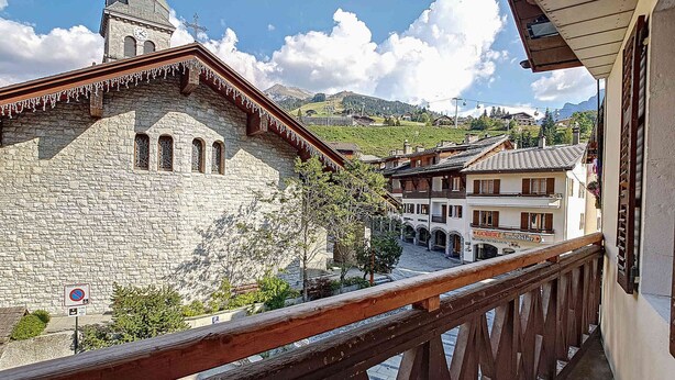 A stone building with a clock tower, a wooden balcony railing, and a sign for a hotel.