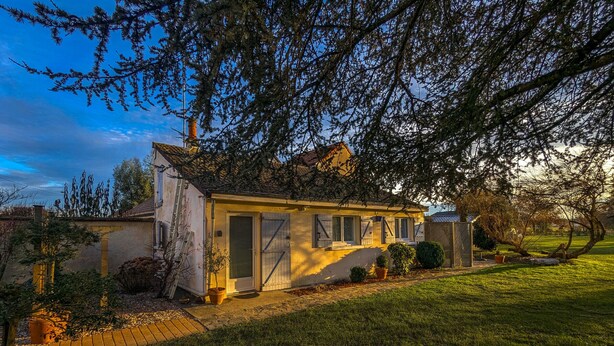 Una casa a un piano con un ingresso, un piccolo portico e un prato curato.