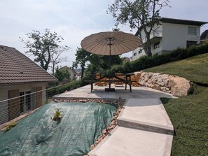 Ein Wohnbereich im Freien mit Schwimmbad, Terrassenmöbeln und einem großen Sonnenschirm.