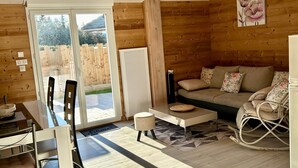 A cozy cabin interior with a wooden interior, a sofa, a dining table with chairs, and a rocking chair. - Charming lodge in Vosges forest with private parking (Granges-Aumontzey-Aumontzey)