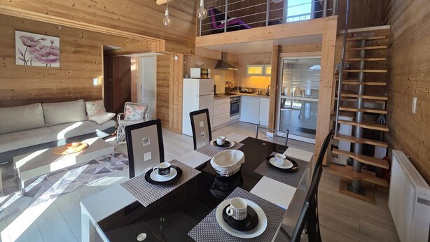 A spacious living area with a sofa, dining table, and kitchen in the background. - Charming lodge in Vosges forest with private parking (Granges-Aumontzey-Aumontzey)