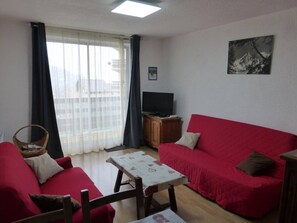 Relax in this inviting living room with a sofa, flat-screen TV, and a small table.