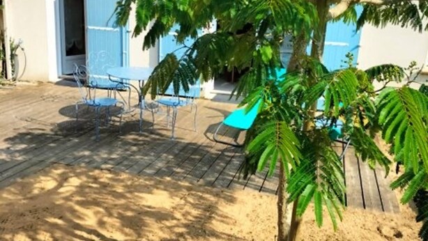 A patio with outdoor furniture, a small tree, and a building with blue shutters. - 3-bedroom house near the beach with private garden and parking (Longeville-sur-Mer)
