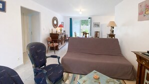 A living room with a sofa, chairs, a small table, and a dining area with a table and chairs. - 3-bedroom house near the beach with private garden and parking (Longeville-sur-Mer)