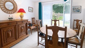 A dining area with a wooden table and chairs, a buffet cabinet, a mirror, and a window with curtains. - 3-bedroom house near the beach with private garden and parking (Longeville-sur-Mer)