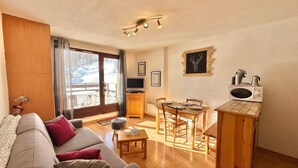 A cozy living room with a sofa, a dining table, and a kitchen area with a microwave.