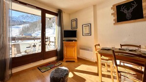 A cozy room with a wooden dining table, chairs, a television, and a framed picture on the wall.