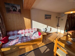 Une pièce chaleureuse avec un canapé en bois, une table à manger et une lampe.