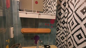 Une salle de bain avec un lavabo, une étagère en bois, un porte-serviettes et un papier peint à motifs.