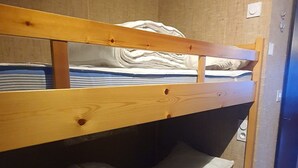 Un lit superposé à deux niveaux, chaque niveau étant équipé d’oreillers et d’une couverture à rayures.