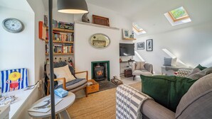A cozy living room with a fireplace, bookshelves, a clock, and a television.