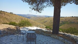 Un patio con dos sillas y una mesa, con vistas a un paisaje montañoso.