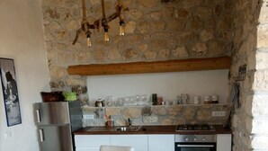 Una cocina con paredes de piedra, una mesa de madera y sillas blancas.