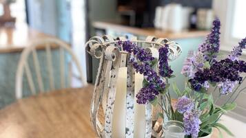 A rustic wooden table with a white vase containing purple flowers and a clear glass bottle.