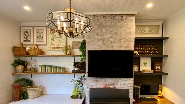 Un salon chaleureux avec une cheminée, des étagères en bois, un téléviseur et un lustre décoratif.