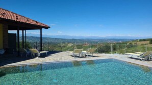 A clear blue pool with lounge chairs and a view of the countryside. - CASA CASTELLA (Diano d'Alba)