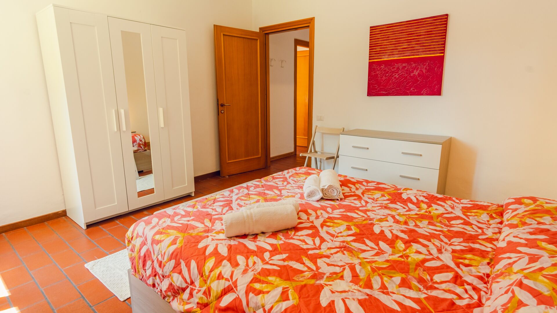 Une chambre à coucher avec un lit, une armoire, une commode et un tableau au mur.