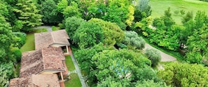 Vista aérea de um bairro residencial com uma casa de telhado inclinado, cercada por vegetação densa e uma pequena trilha.