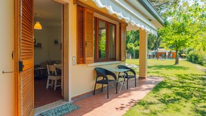 A cozy outdoor seating area with a table and chairs, a door leading to an interior space, and a well-maintained lawn. - Residence Casa Adriana (Costermano sul Garda)