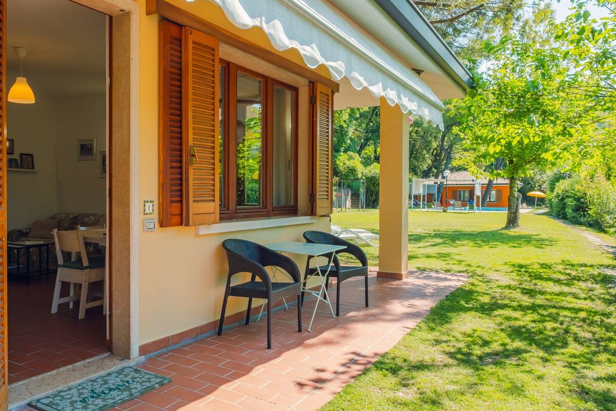 Un espace extérieur accueillant, aménagé avec une table et des chaises, une porte donnant accès à un espace intérieur et une pelouse bien entretenue.