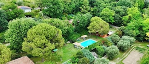 Vista aérea de um bairro residencial com piscina, cercado por muita vegetação e algumas casas.