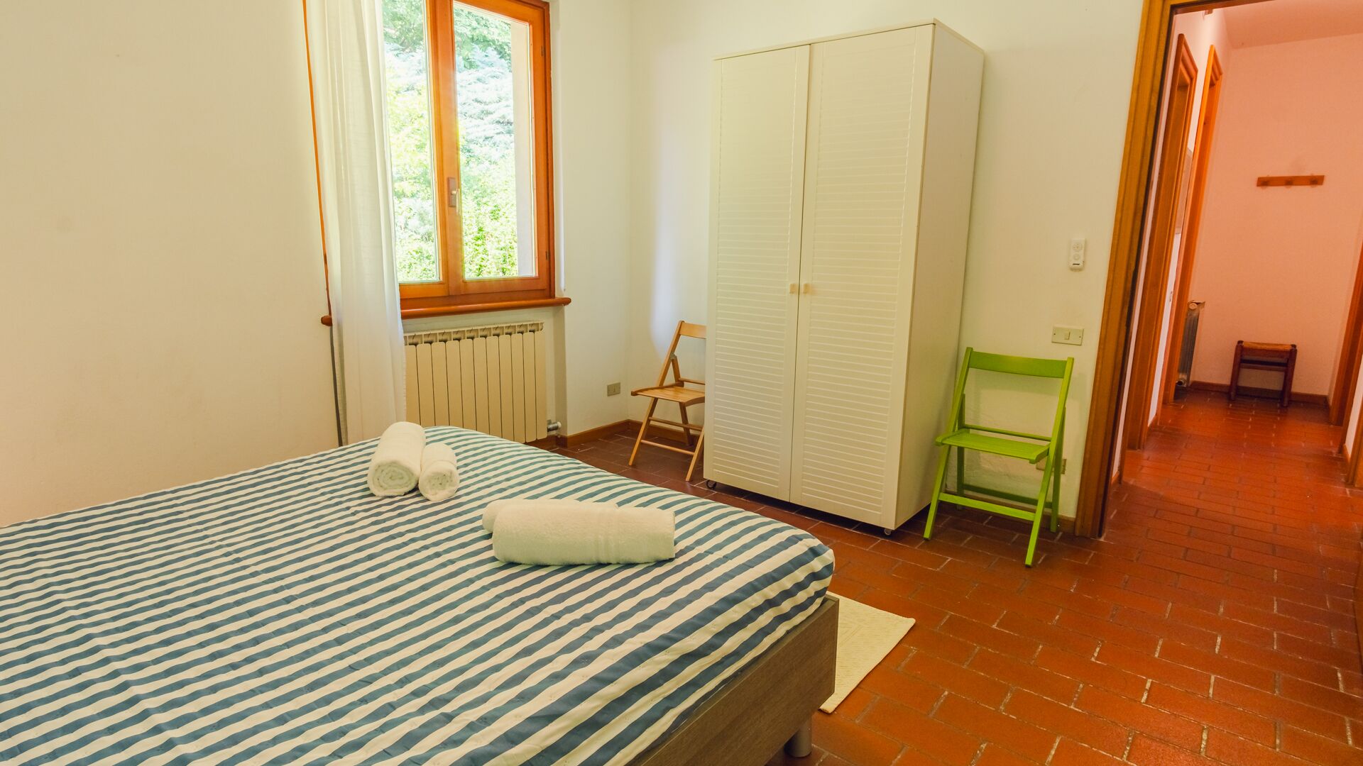 Une chambre à coucher avec un lit, une armoire, une chaise et une fenêtre.