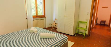 Une chambre à coucher avec un lit, une armoire, une chaise et une fenêtre.
