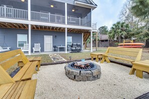 A two-story house with a deck, outdoor seating, and a fire pit.