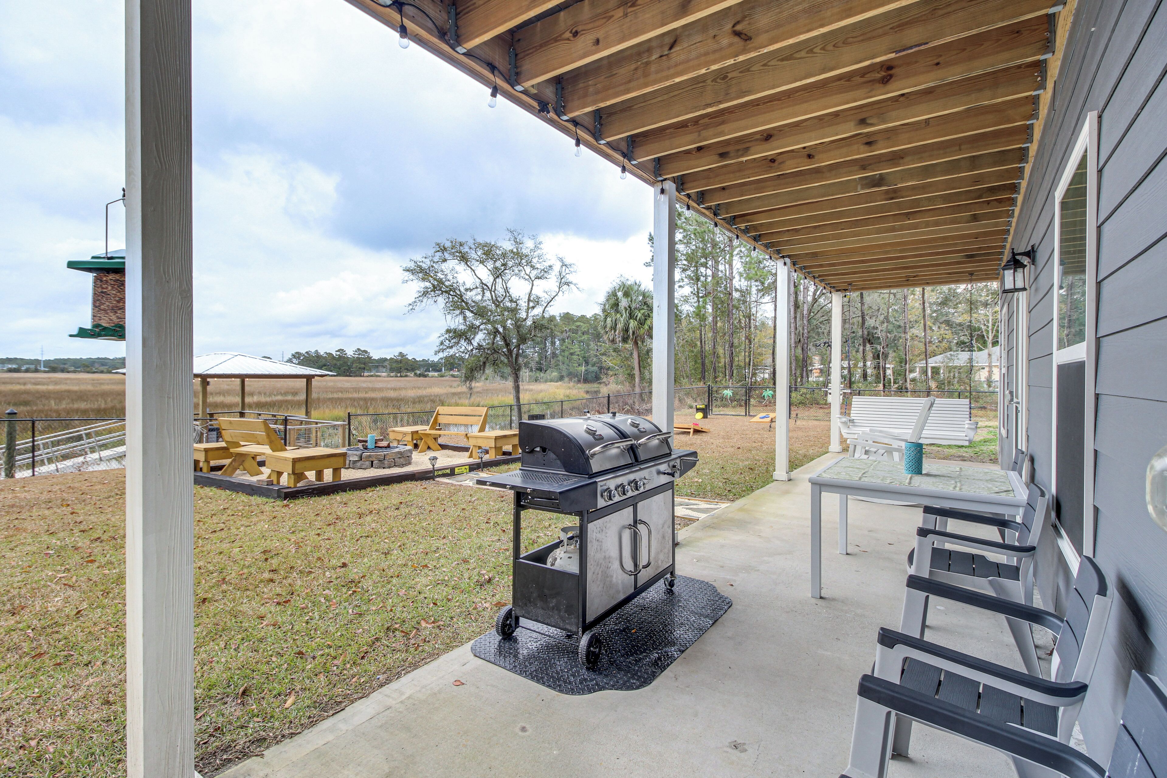 An outdoor patio with a grill, seating, and a view of the surrounding landscape.