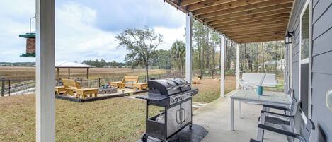 An outdoor patio with a grill, seating, and a view of the surrounding landscape.