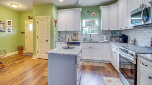 A kitchen with white cabinets, a granite countertop, a microwave, and an oven. - Dock & Fire Pit: Waterfront Midway Retreat! (Midway)