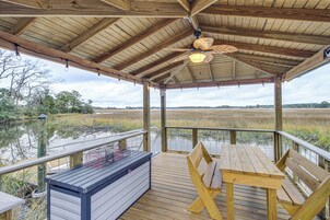 Una terraza de madera con una mesa y bancos, con vistas a una zona pantanosa.