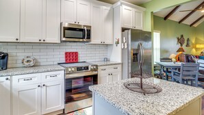 A modern kitchen with white cabinets, stainless steel appliances, and a granite countertop. - Dock & Fire Pit: Waterfront Midway Retreat! (Midway)